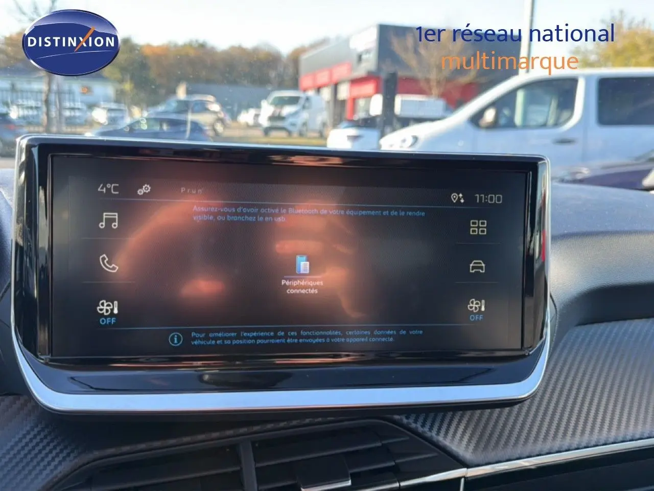 Écran tactile central du tableau de bord d'une Peugeot 208 gris Artense, affichant les options connectées.