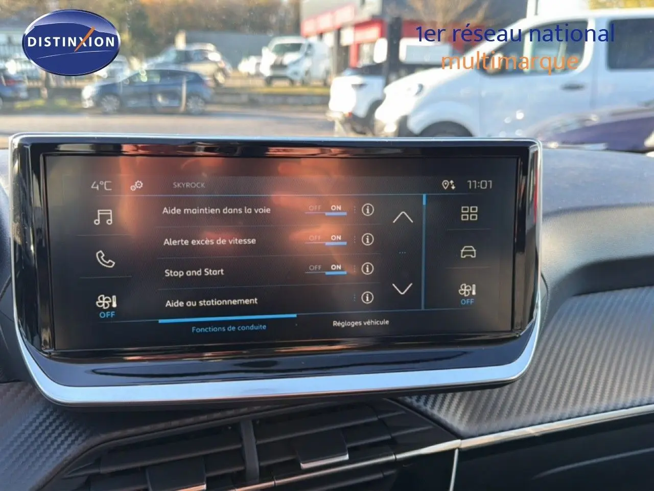 Écran tactile central du tableau de bord de la Peugeot 208 gris Artense, affichant les aides à la conduite en extérieur.