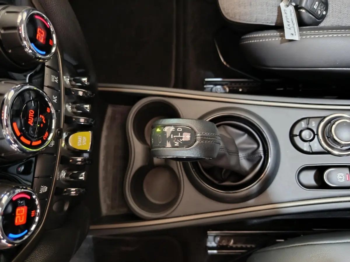 Vue plongeante sur la console centrale du MINI Countryman blanc, avec levier de vitesse automatique et commandes climatisation.