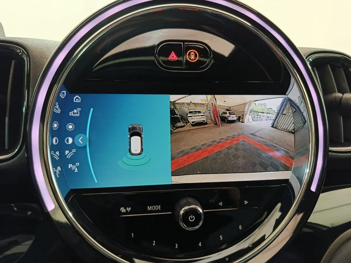 Écran tactile rond affichant la caméra de recul et les capteurs de stationnement du MINI Countryman blanc.