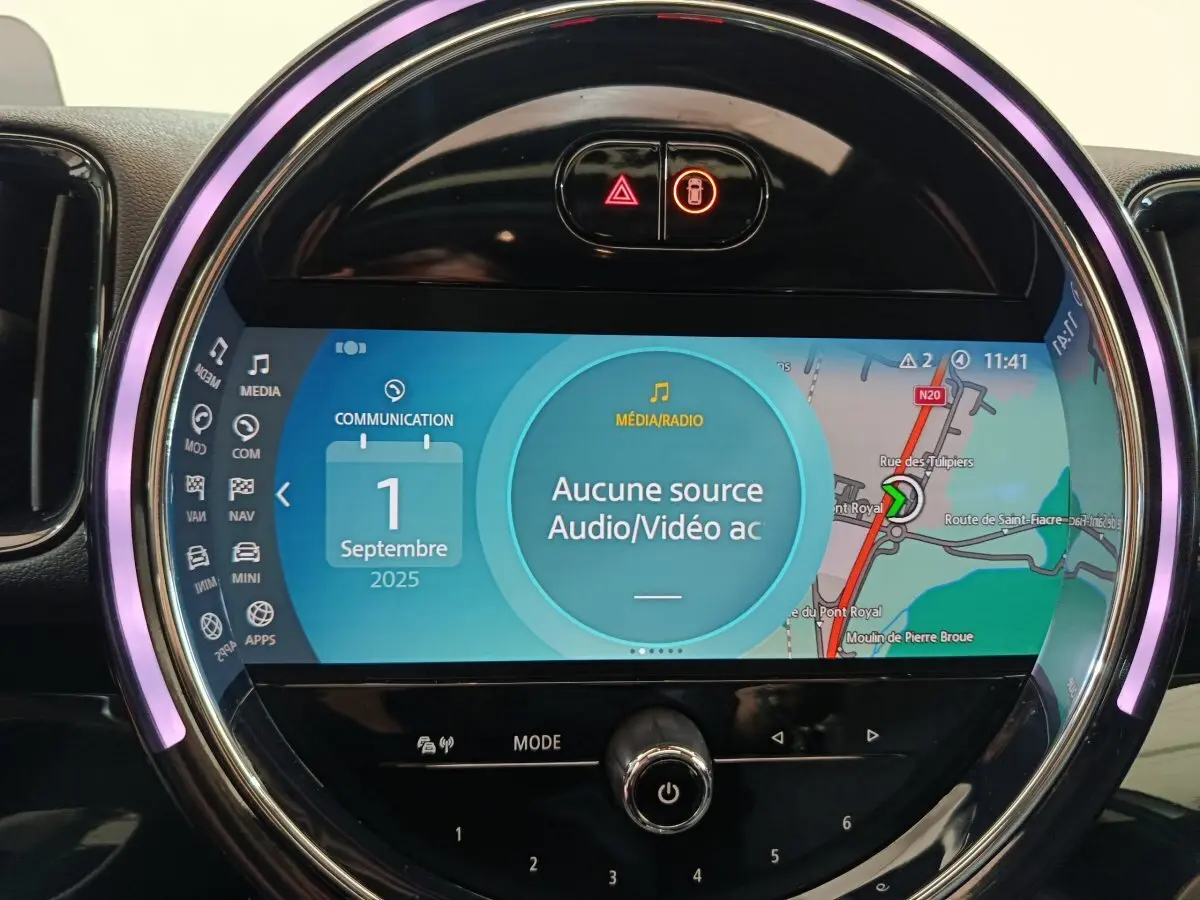 Gros plan sur l'écran tactile circulaire du tableau de bord de la MINI Countryman blanc, affichant la navigation et médias.