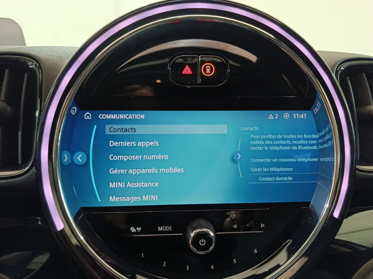 Écran tactile central circulaire allumé avec menu communication dans l'habitacle noir du MINI Countryman blanc.