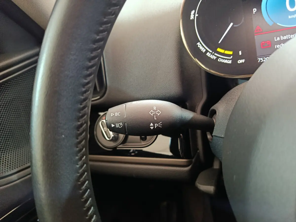 Gros plan sur le commodo gauche du volant cuir noir d'un MINI Countryman blanc, avec tableau de bord digital en arrière-plan.