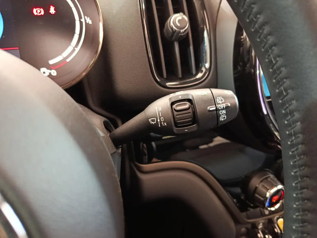 Gros plan sur la commande d'essuie-glace à gauche du volant cuir noir du MINI Countryman blanc hybride rechargeable.