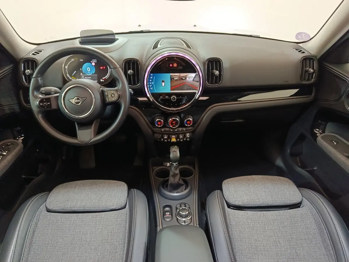 Intérieur du MINI Countryman Cooper SE 2021 vu de face, tableau de bord noir avec écran tactile circulaire et sièges gris.