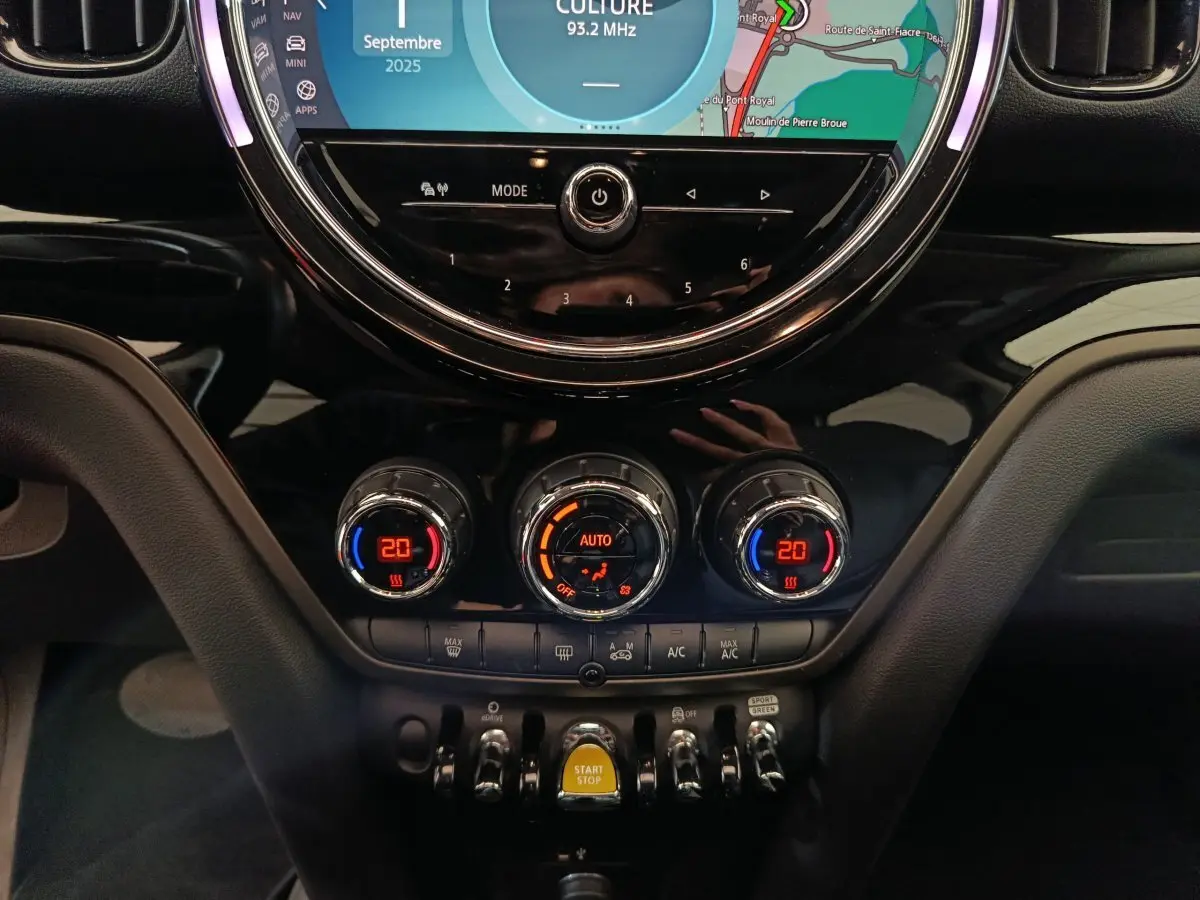 Détail du tableau de bord noir du MINI Countryman hybride avec commandes climatisation et bouton Start/Stop jaune.