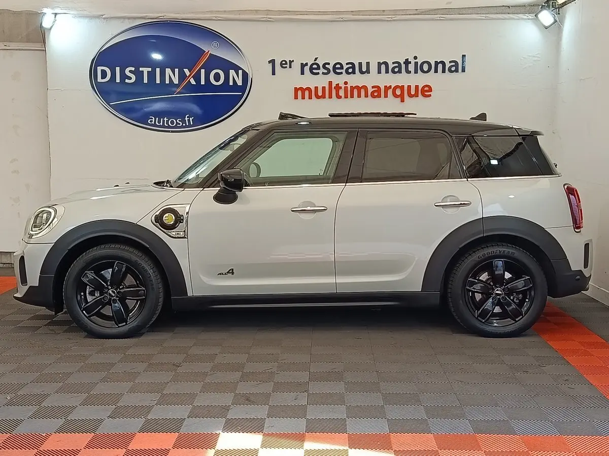 Profil côté gauche d'une MINI Countryman Cooper SE hybride blanche avec toit noir et jantes noires brillantes.