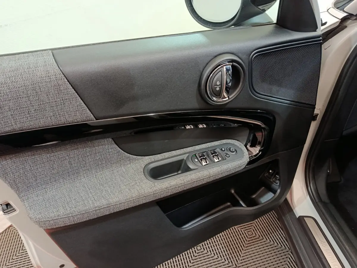Intérieur côté gauche de la porte avant blanche du MINI Countryman 2021, avec garniture tissu gris et commandes électriques.