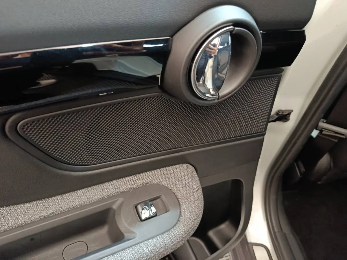 Détail de la porte côté droit blanche d'une MINI Countryman 2021 avec poignée chromée et habillage tissu gris.