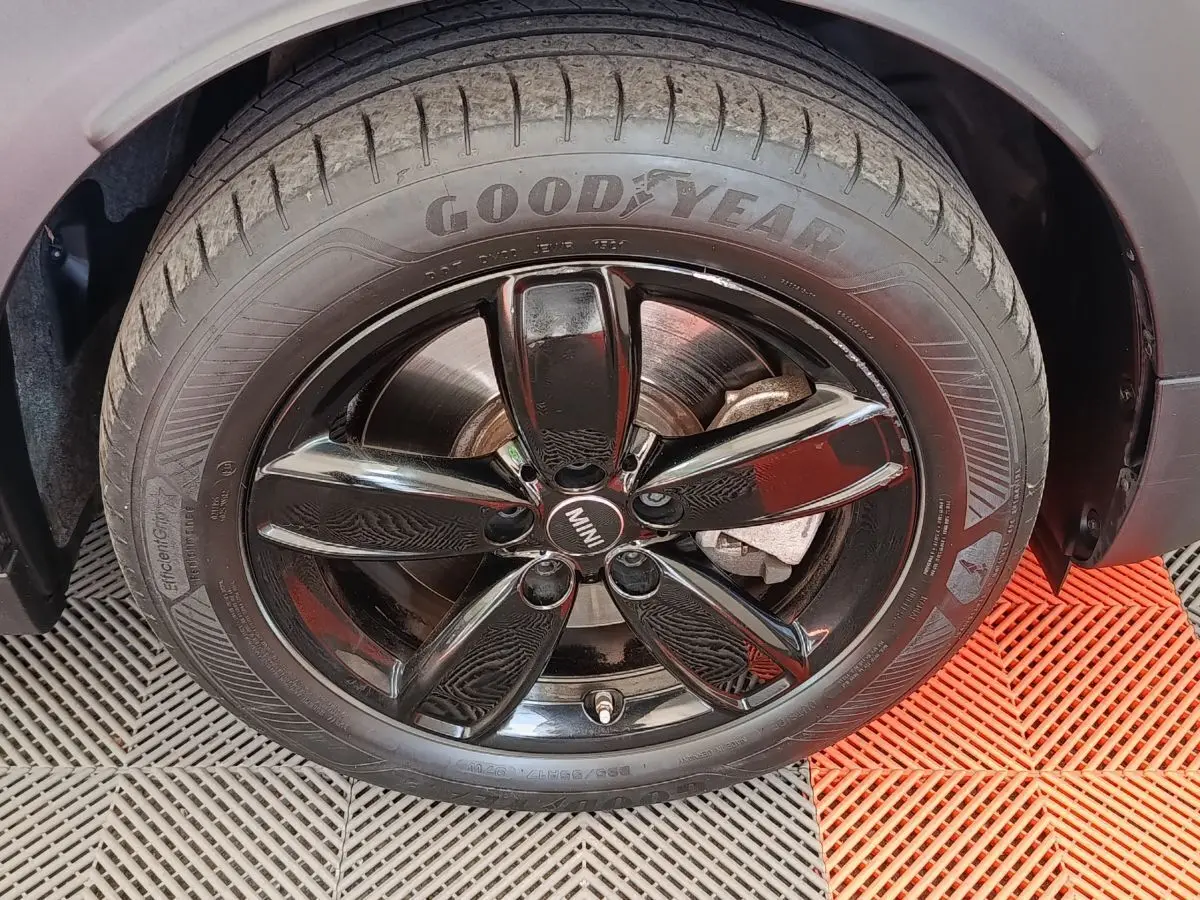 Gros plan sur la roue avant droite du MINI Countryman blanc avec jante noire brillante et pneu Goodyear.