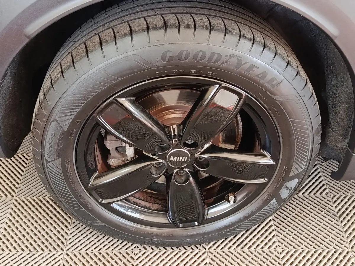 Gros plan sur la roue avant droite d'une MINI Countryman blanche, jante noire brillante et pneu Goodyear.