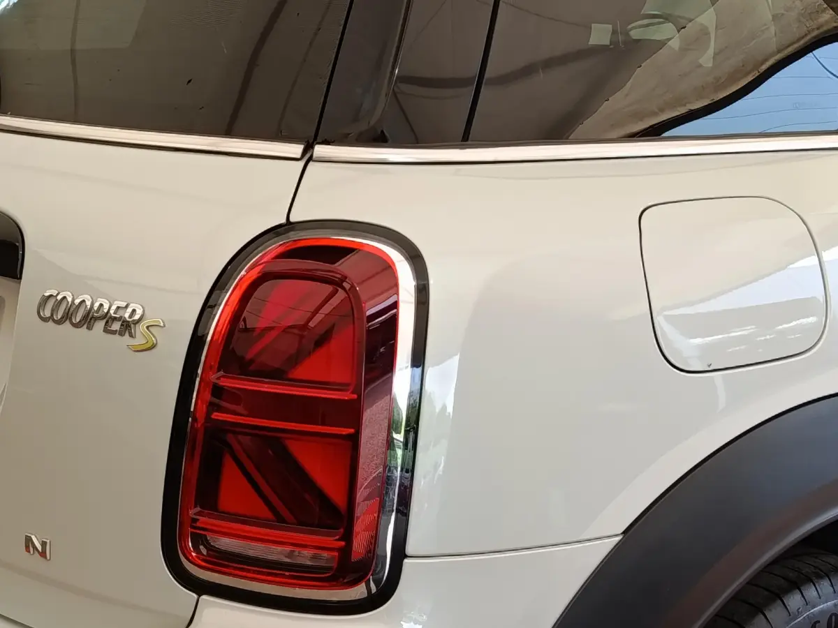 Gros plan sur le feu arrière gauche rouge et l'insigne Cooper S d'une MINI Countryman blanche hybride rechargeable.