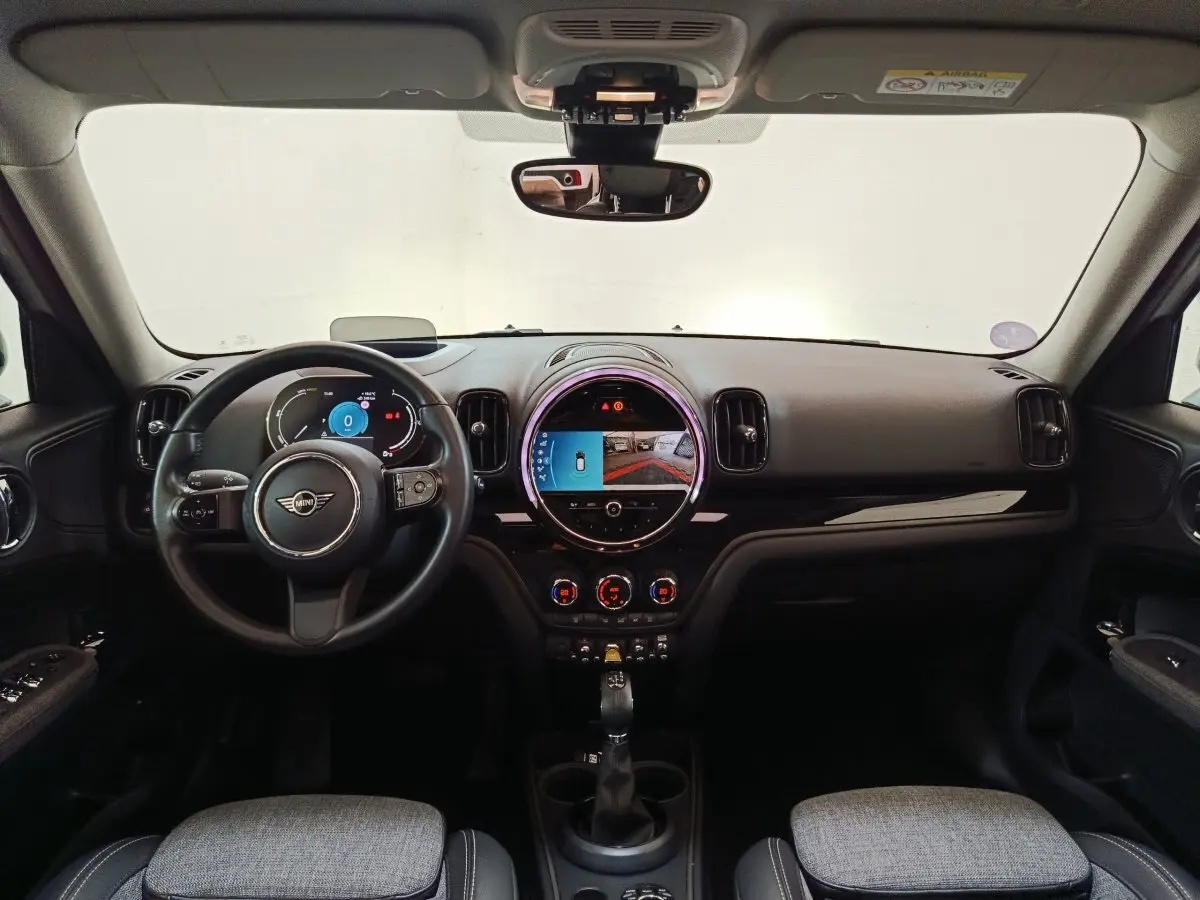Intérieur noir et gris du MINI Countryman Cooper SE, vue frontale sur tableau de bord et écran tactile central rond.