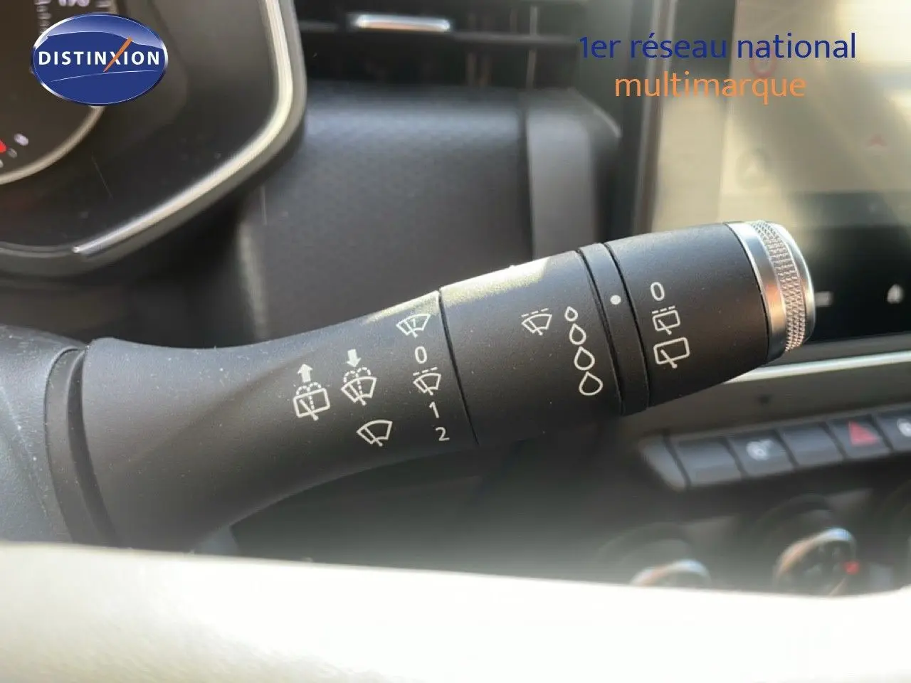 Gros plan sur la commande des essuie-glaces dans l'habitacle d'une Renault Clio blanc glacier 2020.