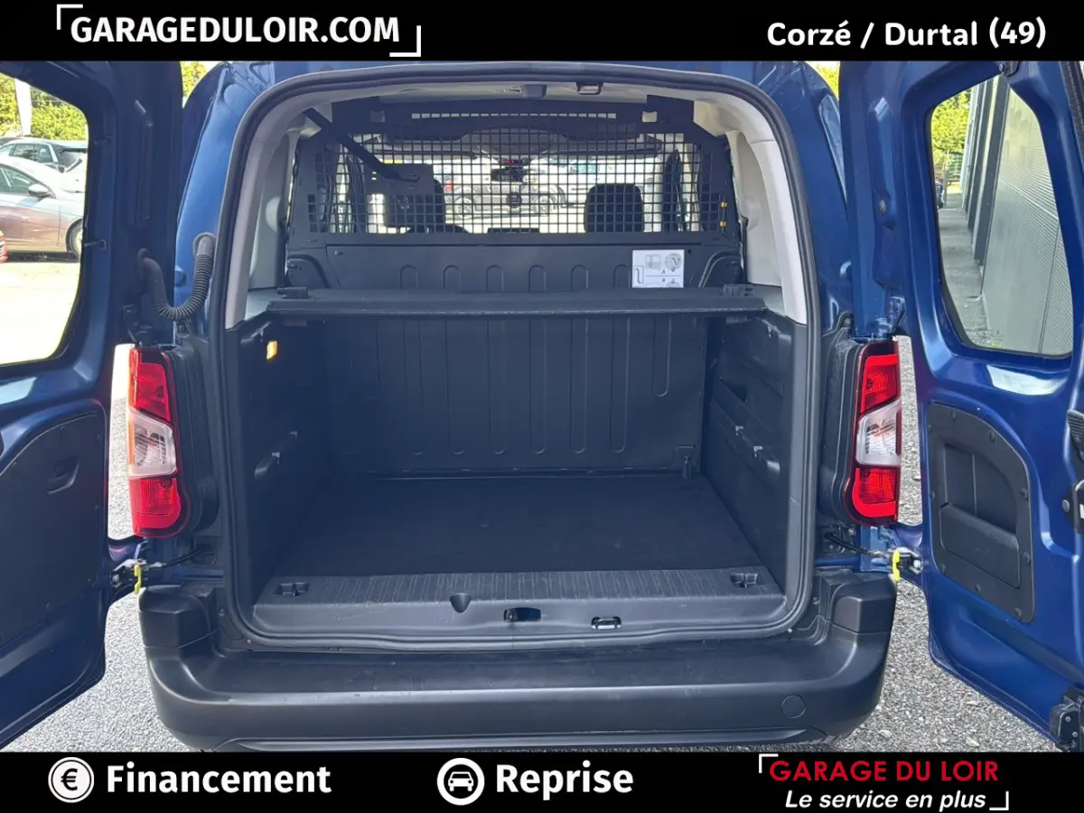 Vue arrière ouverte du Peugeot Rifter bleu 2024 montrant le grand espace de coffre avec séparation grillagée intérieure.