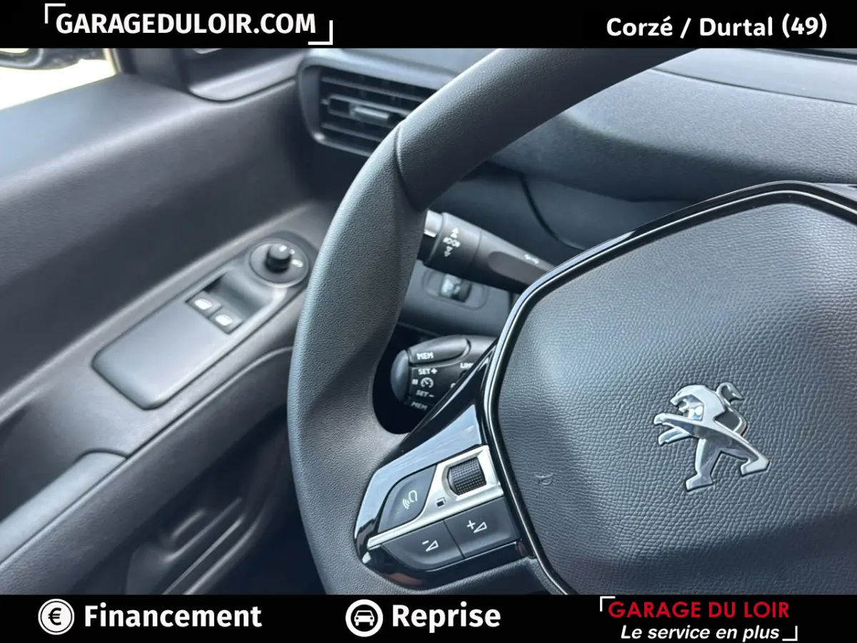 Gros plan sur le volant Peugeot et la portière côté gauche avec commandes électriques, intérieur noir.