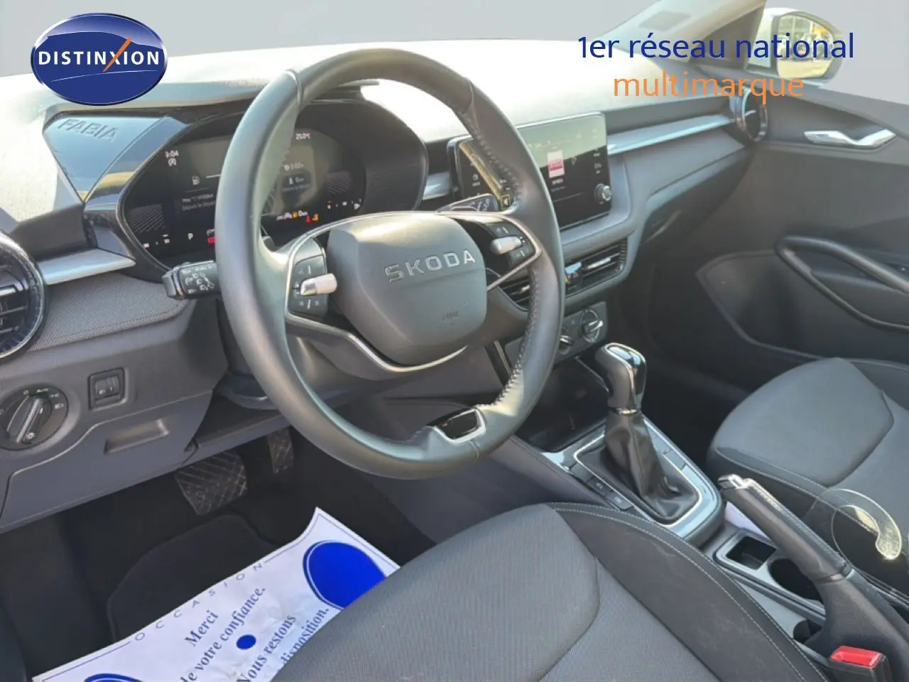 Vue intérieure côté conducteur du tableau de bord et volant noir de la Skoda Fabia 2025 avec boîte automatique et sellerie tissu.