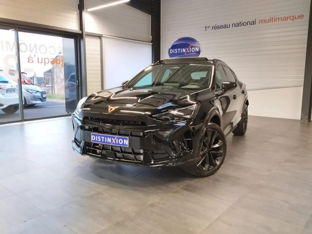 Vue 3/4 avant d'une CUPRA Formentor noire métal avec jantes noires et logo CUPRA sur le capot, en showroom.