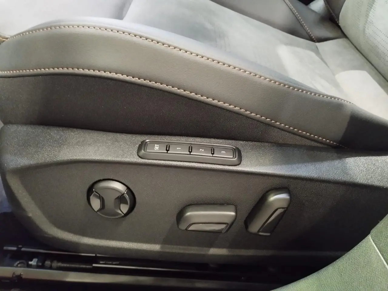 Détail des commandes de réglage électrique du siège conducteur en suédine noire avec surpiqûres cuivrées dans une CUPRA Formentor noir métal.