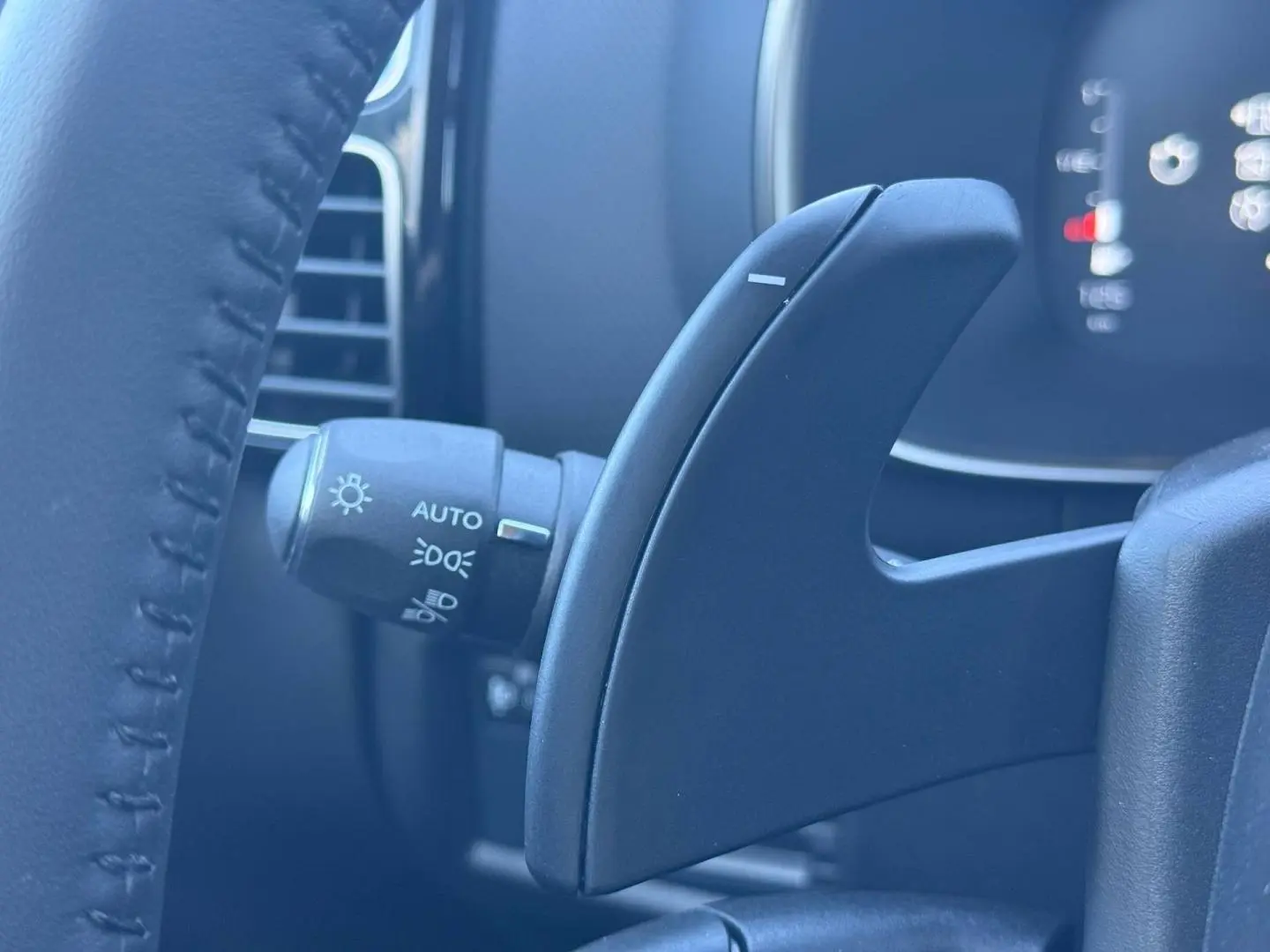 Gros plan sur la palette de changement de vitesses derrière le volant du Citroën C5 Aircross noir, avec commandes d’éclairage visibles.
