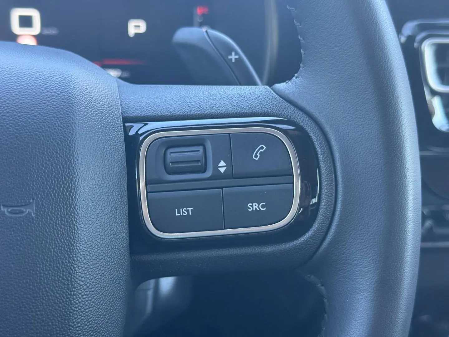 Gros plan sur les commandes gauche du volant noir du Citroën C5 Aircross 2025 avec boutons de gestion audio et appel.