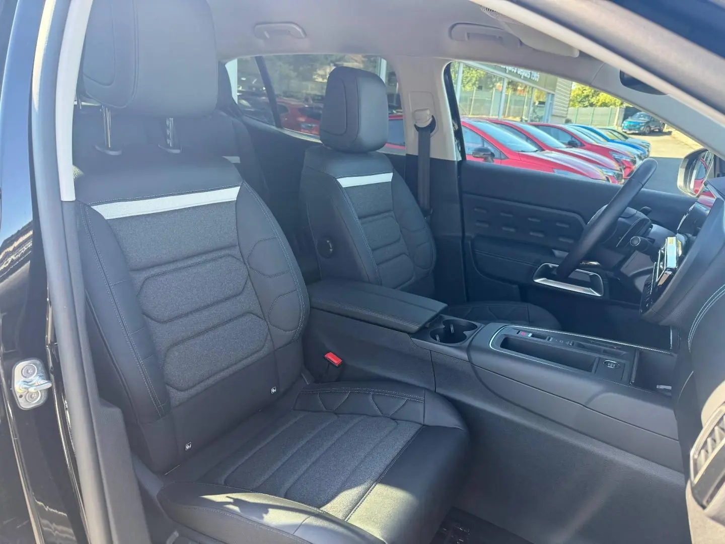 Vue intérieure côté avant gauche du Citroën C5 Aircross noir Perla Nera, sièges tissu et cuir noir avec accoudoir central.