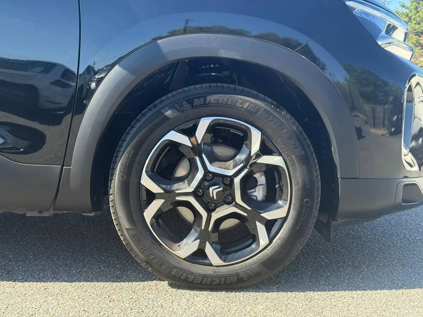 Gros plan sur la roue avant gauche du Citroën C5 Aircross noir Perla Nera avec jante alu bicolore et pneu Michelin.