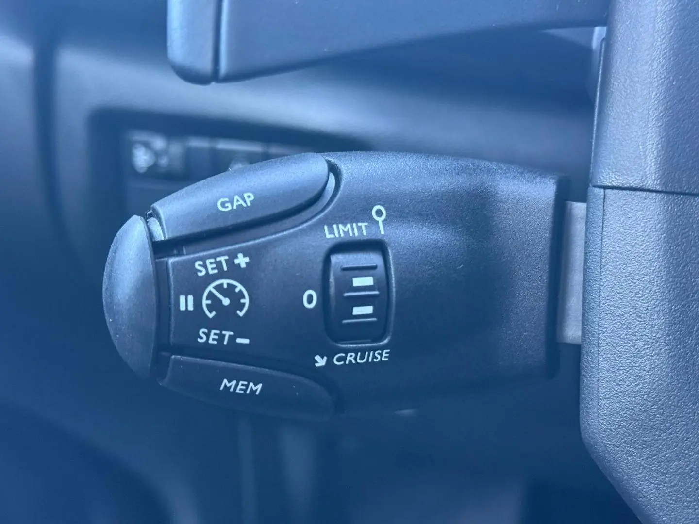 Gros plan sur la commande de régulateur de vitesse et limiteur sur le côté gauche du volant du Citroën C5 Aircross noir.