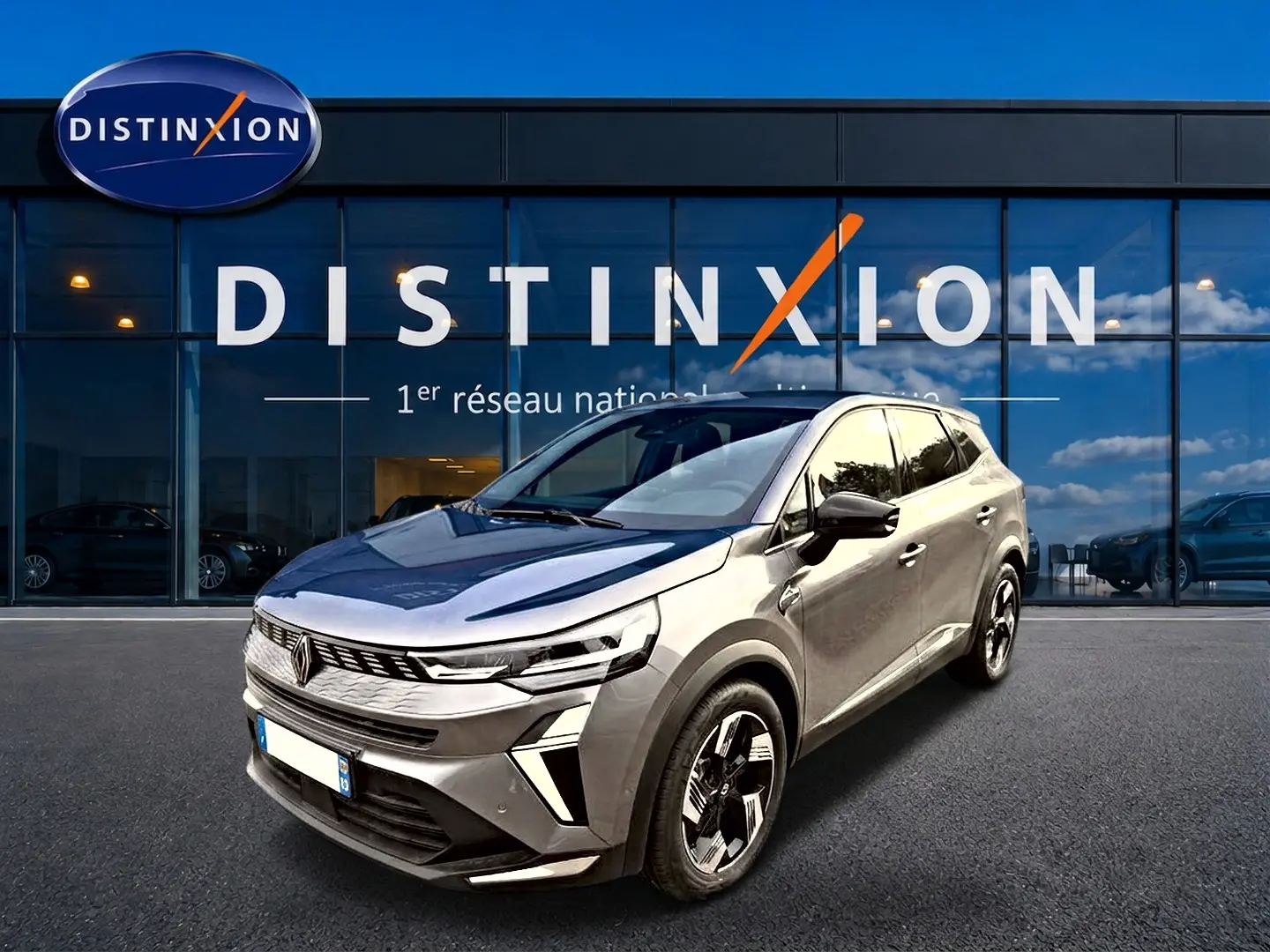 Renault Symbioz 2026 gris cassiope en 3/4 avant, avec jantes alu et feux LED, devant un showroom Distinxion.