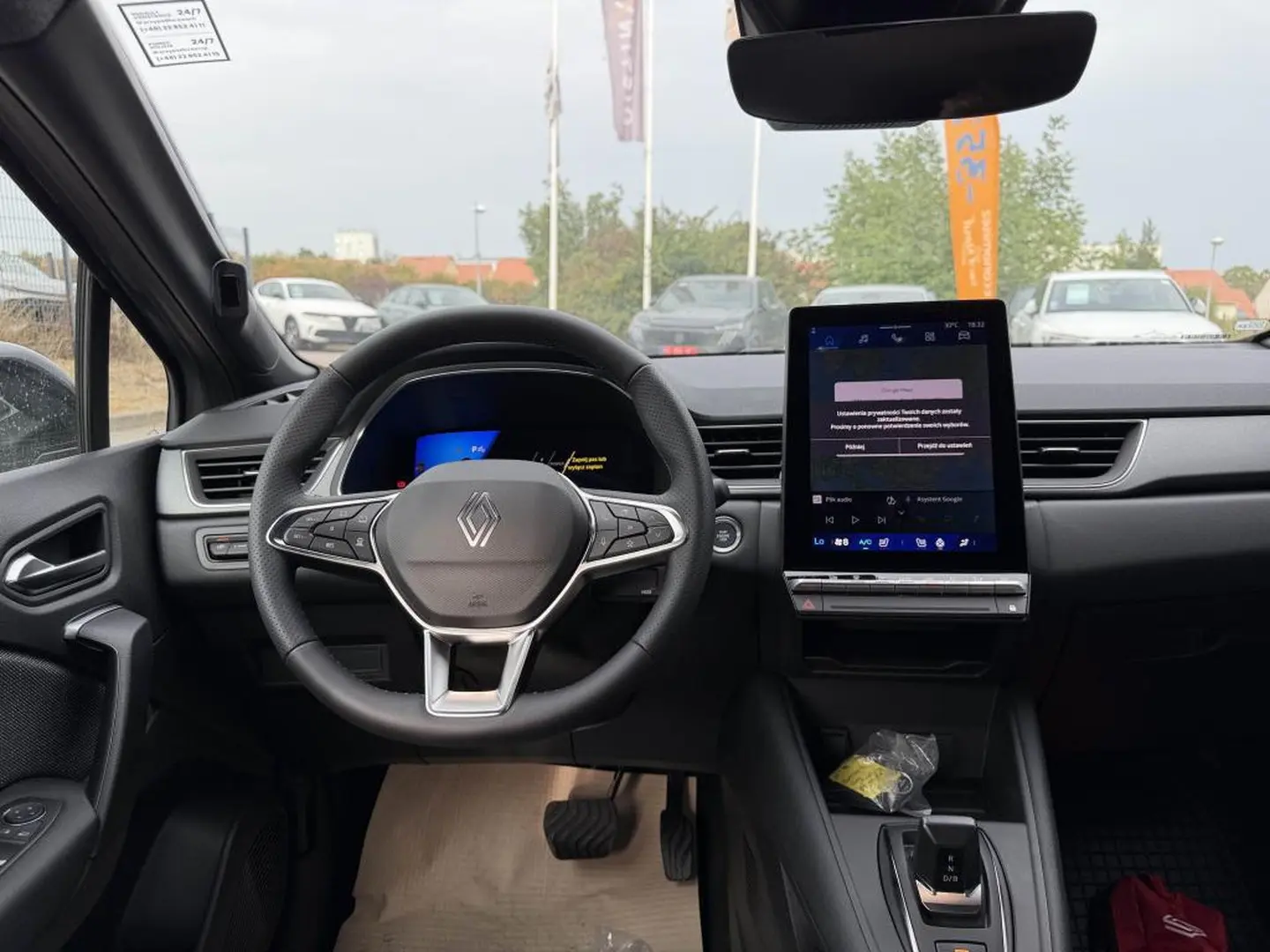 Vue intérieure frontale du tableau de bord et volant Renault Symbioz gris cassiope avec écran tactile vertical et commandes au volant.
