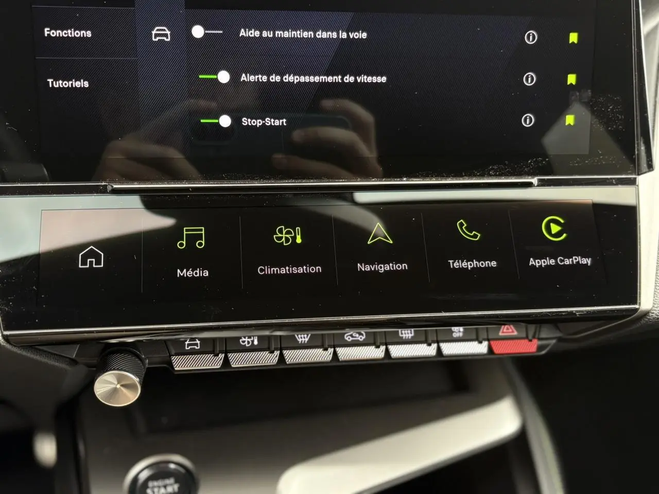 Vue rapprochée de l'écran tactile central et des commandes tactiles du Peugeot 308 2024 blanc, affichant navigation et Apple CarPlay.