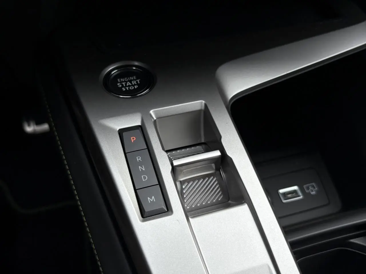 Gros plan sur la console centrale argentée de la Peugeot 308 2024 avec bouton start/stop et commandes de boîte auto.