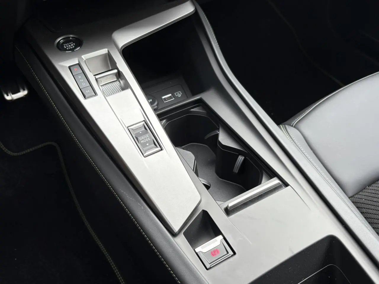 Console centrale de la Peugeot 308 GT 2024 avec levier de vitesses automatique et bouton Drive Mode, sellerie noire.