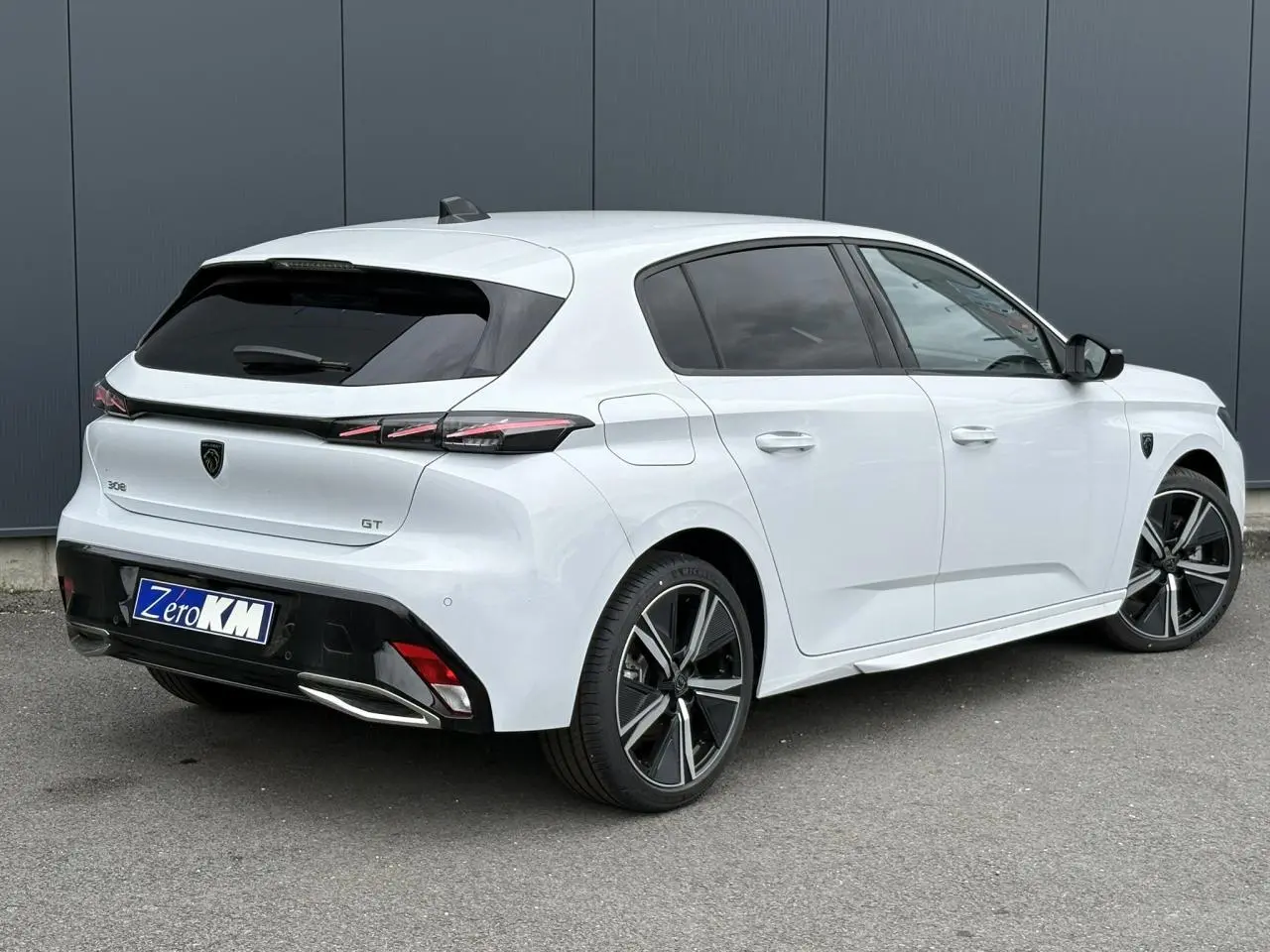 Peugeot 308 GT blanc Okenite vue 3/4 arrière droit, jantes alliage 18'' et feux LED distinctifs.