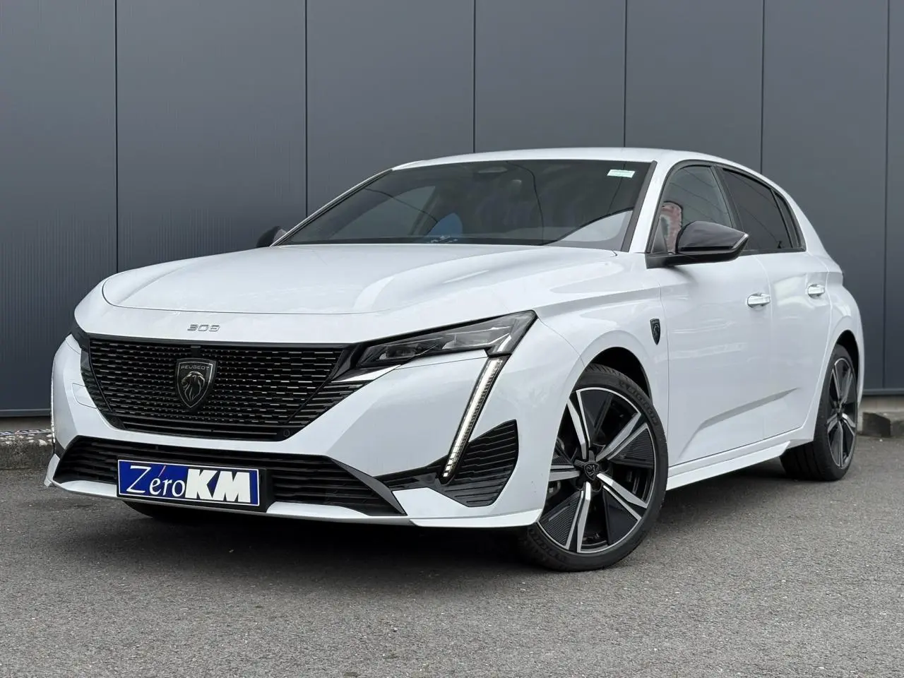 Peugeot 308 2024 blanc Okenite en 3/4 avant droit, avec calandre noire et jantes alliage 18 pouces.