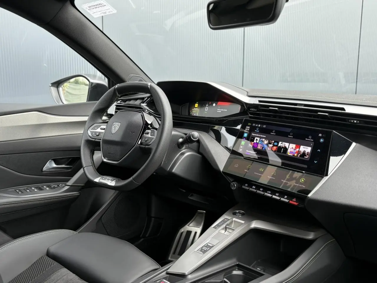 Vue intérieure côté conducteur du Peugeot 308 2024, mettant en valeur le volant cuir et l'écran tactile central.