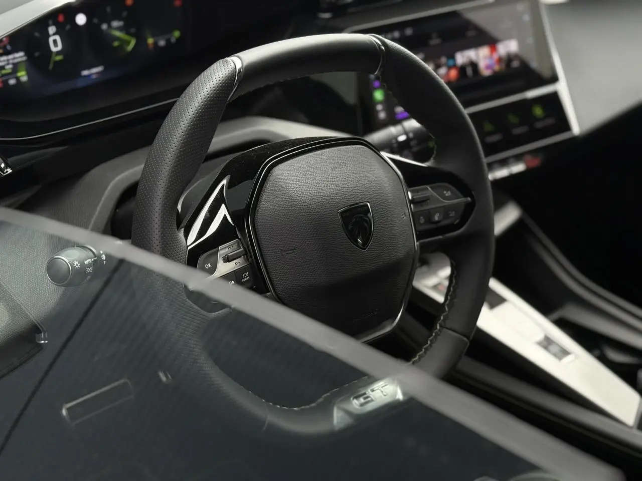 Gros plan sur le volant cuir noir de la Peugeot 308 GT 2024, avec commandes intégrées et logo central.