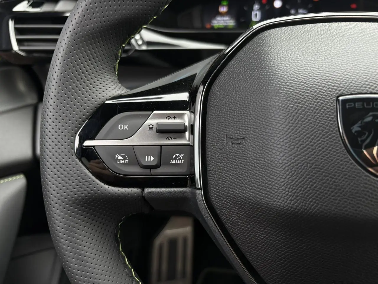 Gros plan sur le volant cuir perforé avec commandes intégrées du Peugeot 308 GT 2024 blanc Okenite.