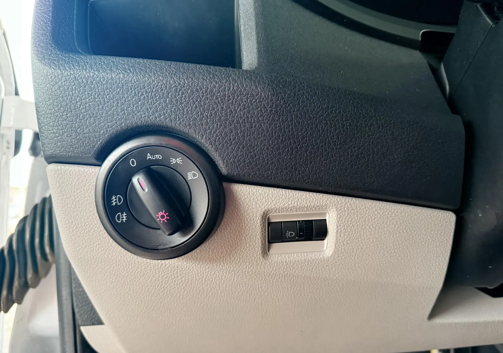 Détail du tableau de bord côté gauche du Volkswagen Transporter blanc 2018, avec commande des phares et réglage de l’éclairage.