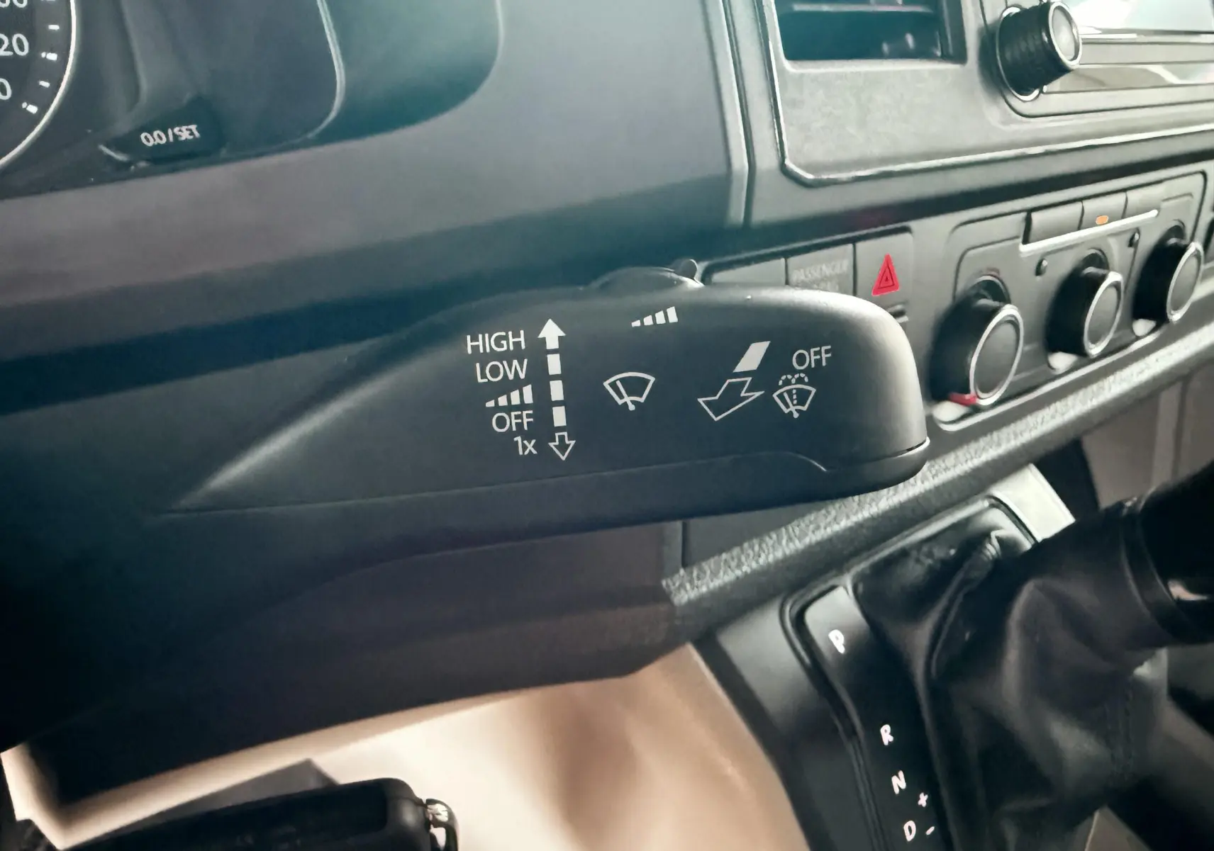 Gros plan sur la commande d’essuie-glace et la console centrale du Volkswagen Transporter blanc, vue intérieure côté conducteur.