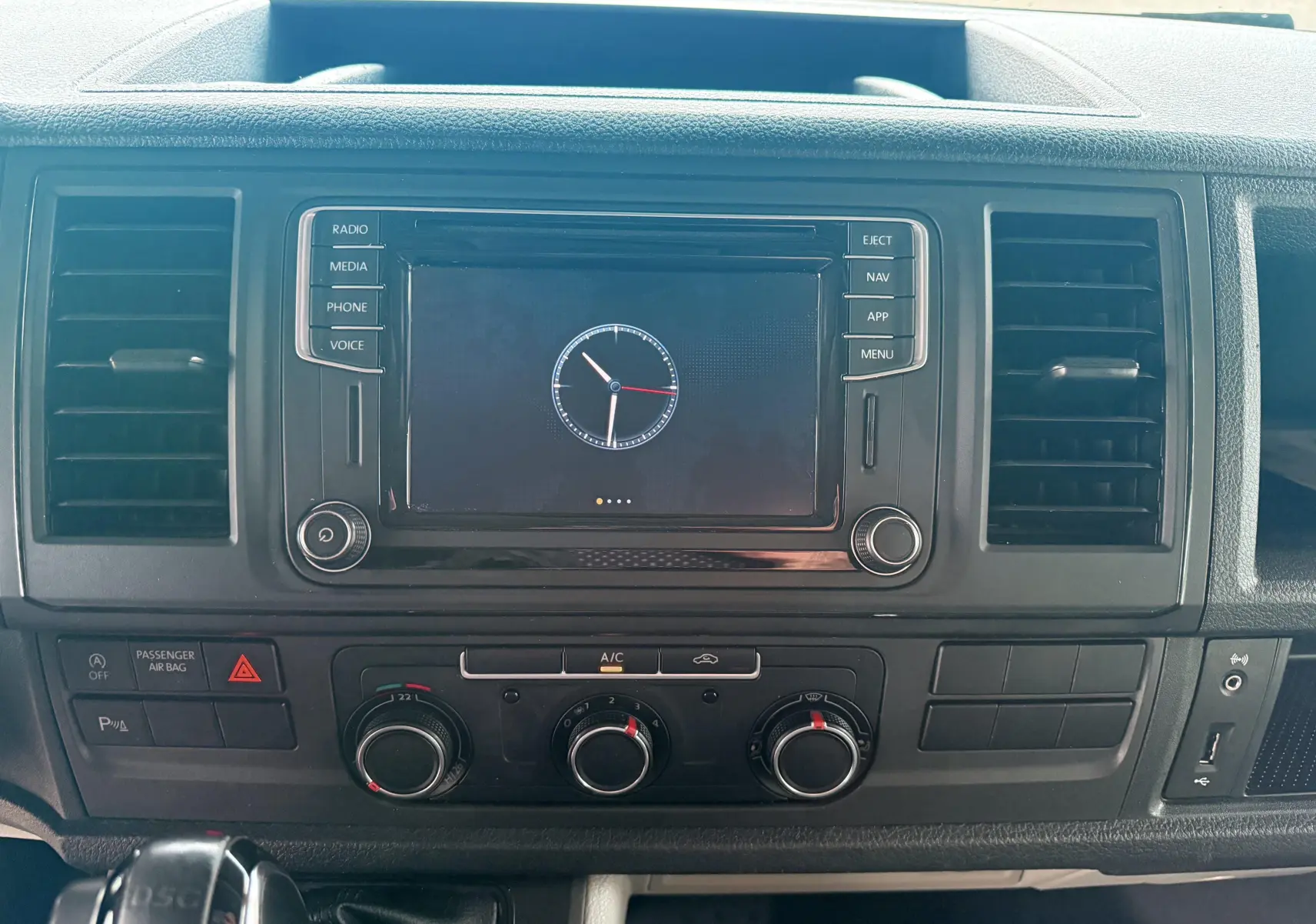 Vue rapprochée du tableau de bord noir du Volkswagen Transporter L1H1 2018 avec écran central et commandes de climatisation.