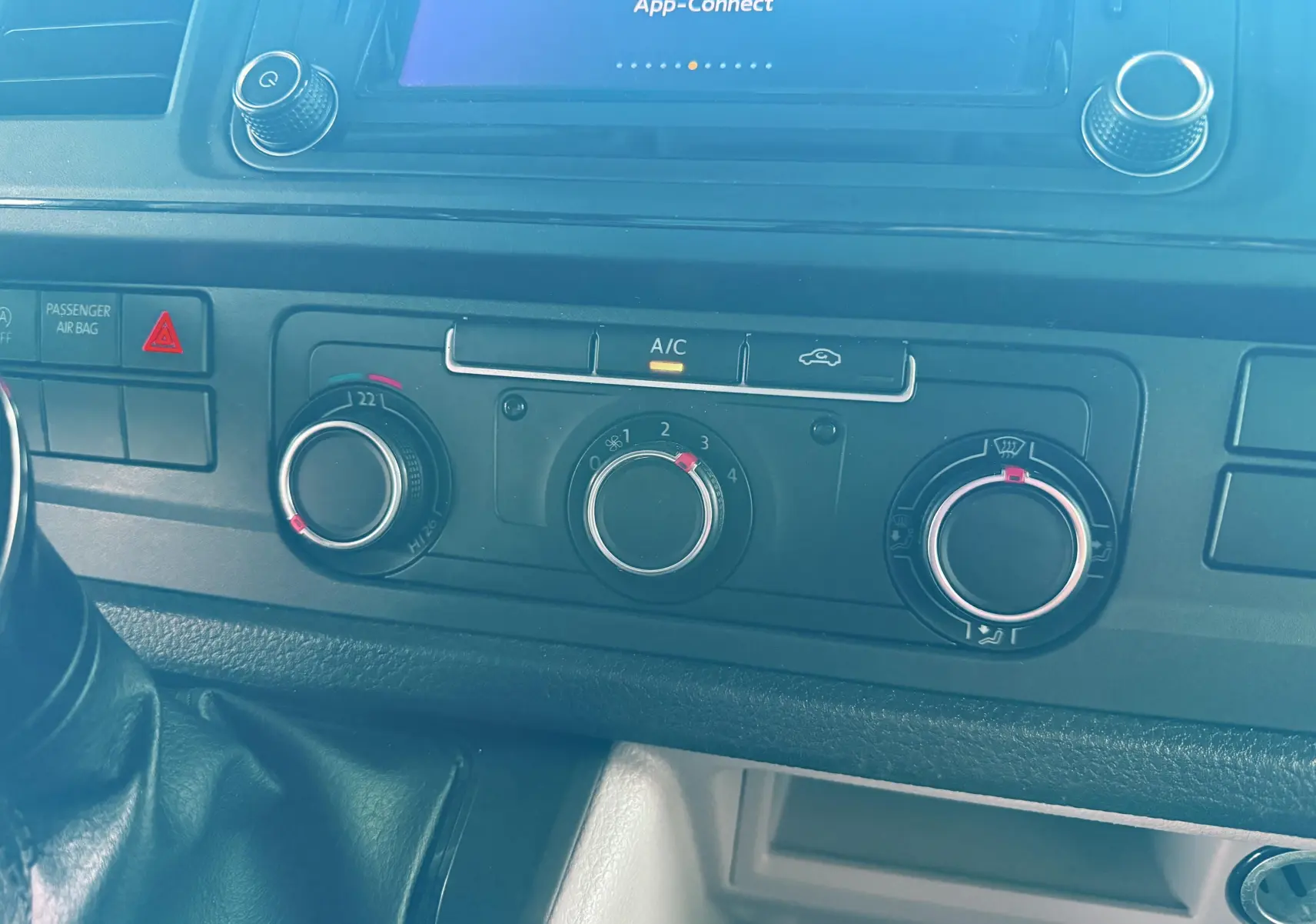 Vue rapprochée du tableau de bord du Volkswagen Transporter blanc 2018, montrant les commandes de climatisation et la console centrale.