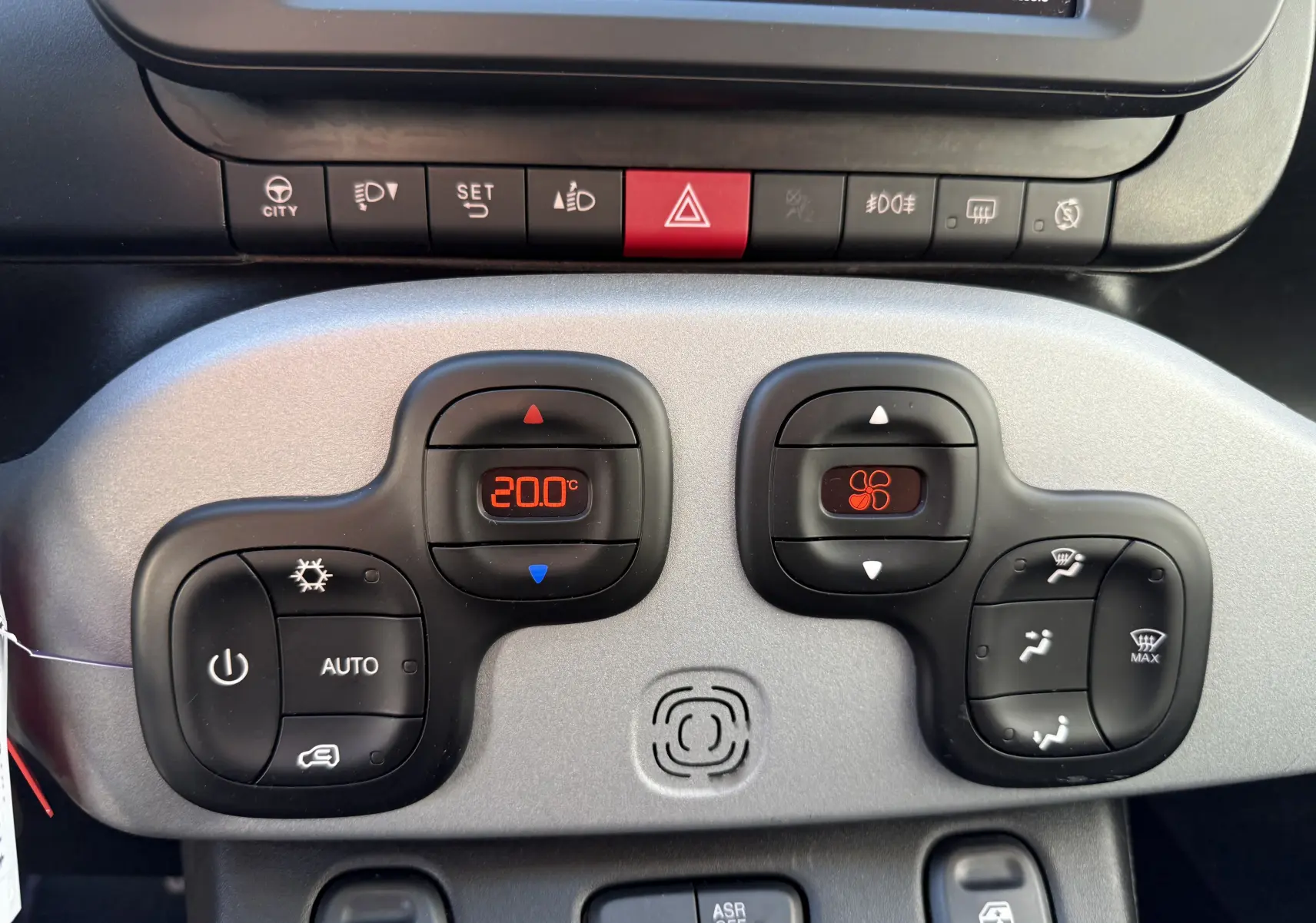 Gros plan sur la console centrale grise du Fiat Panda City Cross 2023, affichant la climatisation digitale et les commandes.