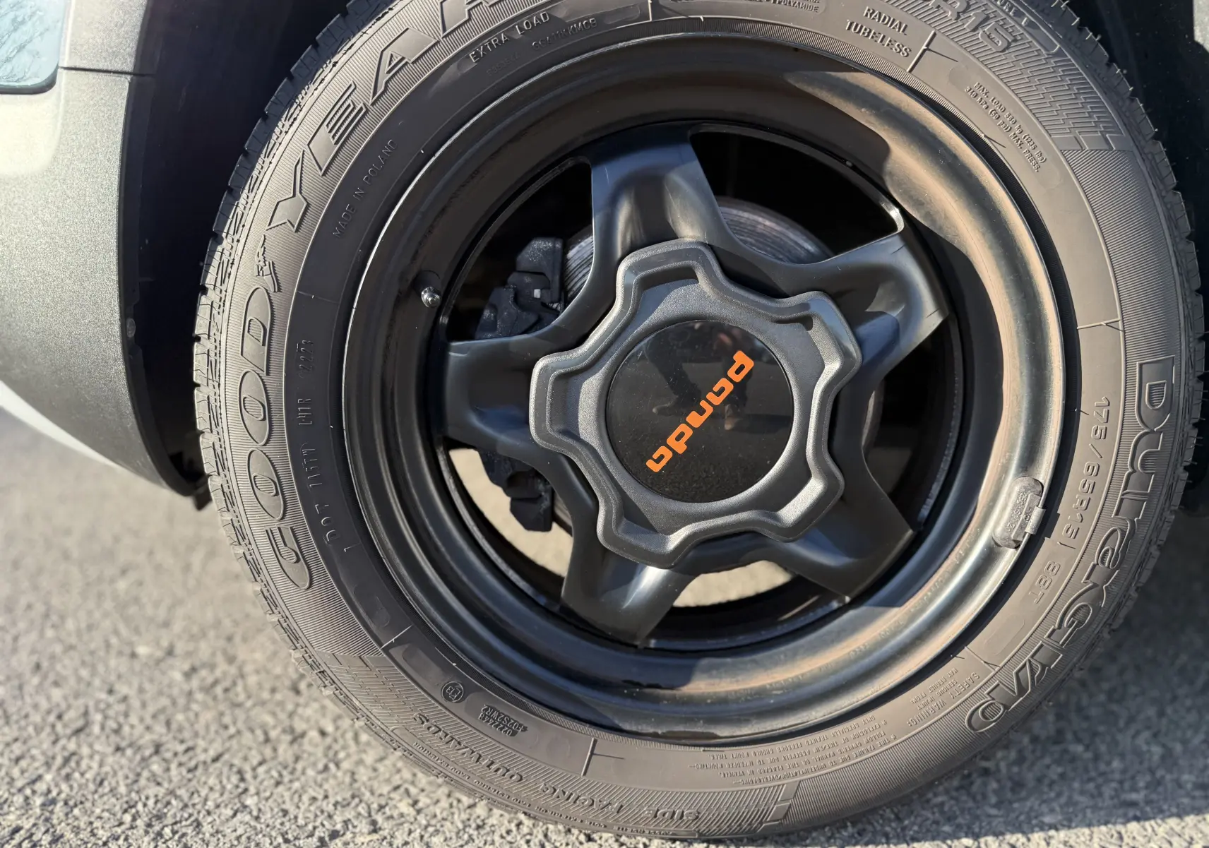 Gros plan sur la roue avant droite de la Fiat Panda City Cross gris minuit avec jante noire et logo orange Panda.