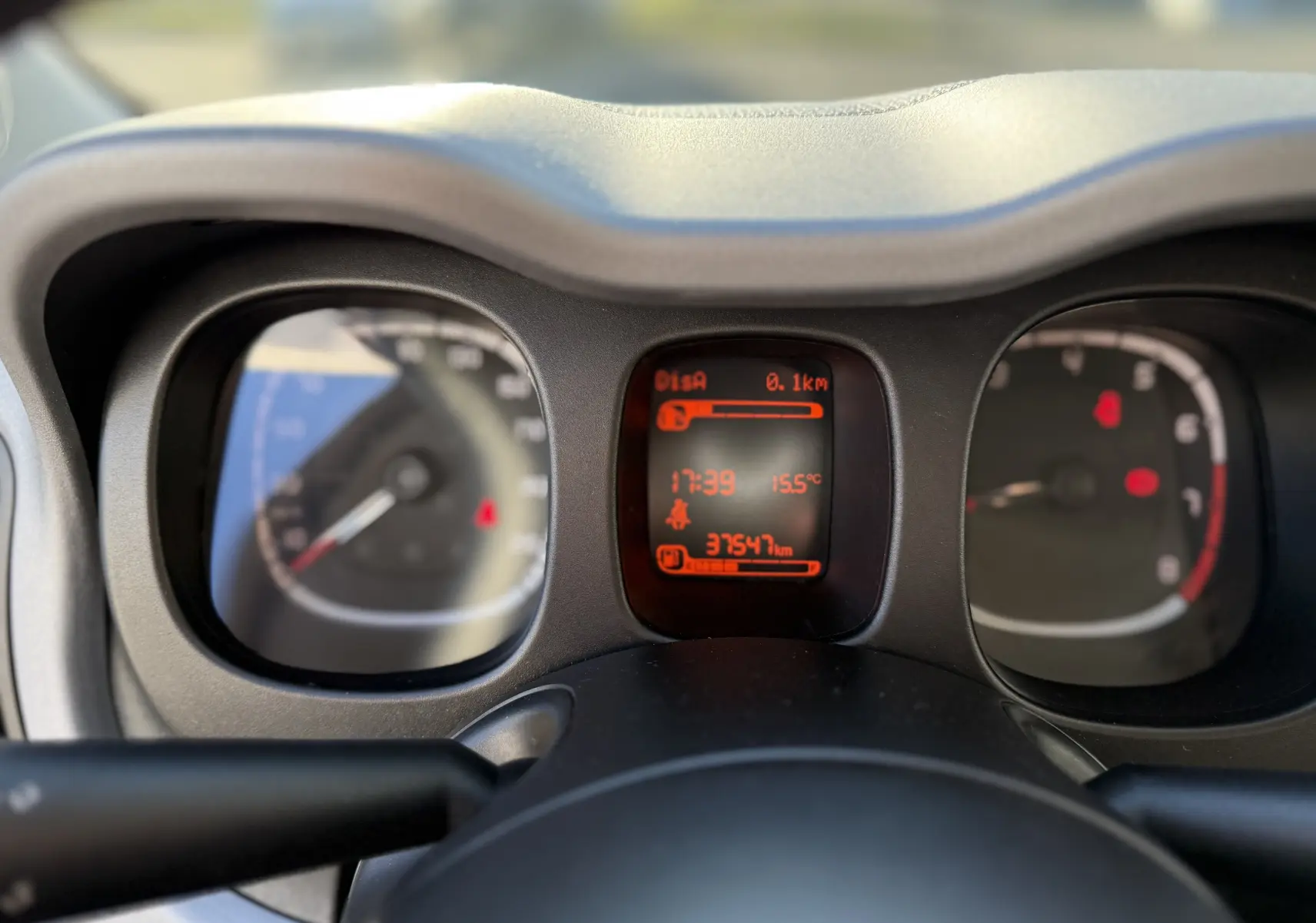 Vue rapprochée du tableau de bord de la Fiat Panda City Cross 2023, affichage digital orange au centre.