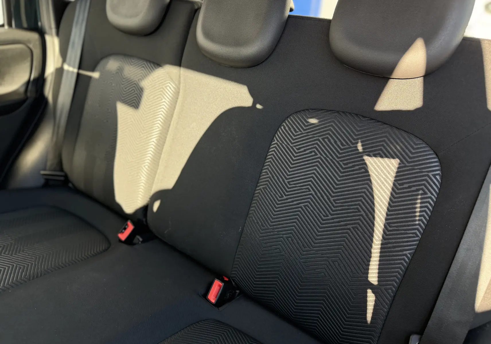 Vue rapprochée des sièges arrière en tissu noir avec motifs géométriques de la Fiat Panda City Cross gris minuit 2023.