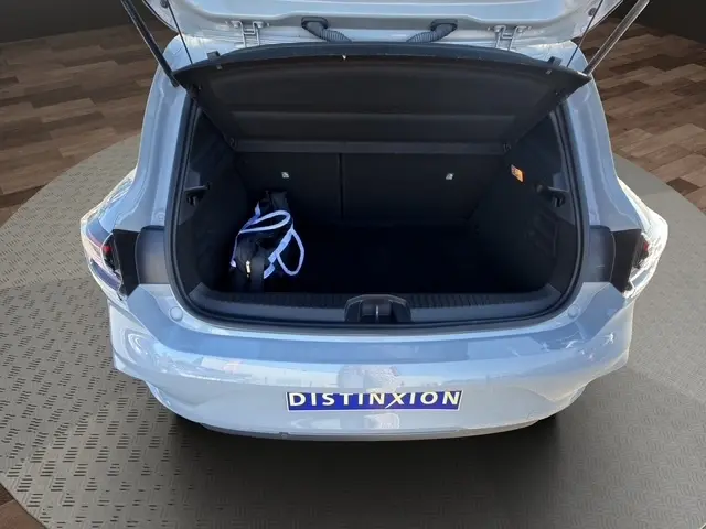 Coffre ouvert vu de l'arrière d'une Renault Clio Esprit Alpine gris clair, avec un sac noir à l'intérieur.