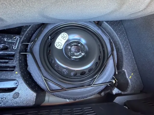 Roue de secours compacte noire avec étiquette de vitesse dans le coffre d'une Renault Clio gris clair 2025.