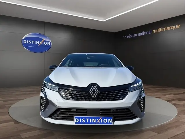 Vue de face d'une Renault Clio Esprit Alpine E-Tech gris clair, avec calandre noire et feux LED allumés en showroom.