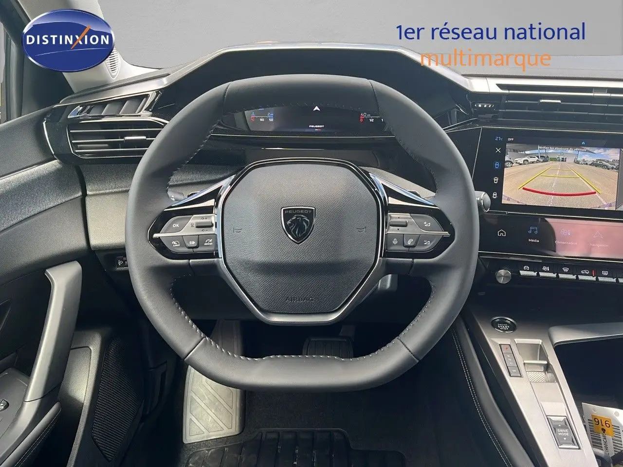 Vue intérieure centrée sur le volant Peugeot 308 2024, avec tableau de bord numérique et écran de caméra de recul.